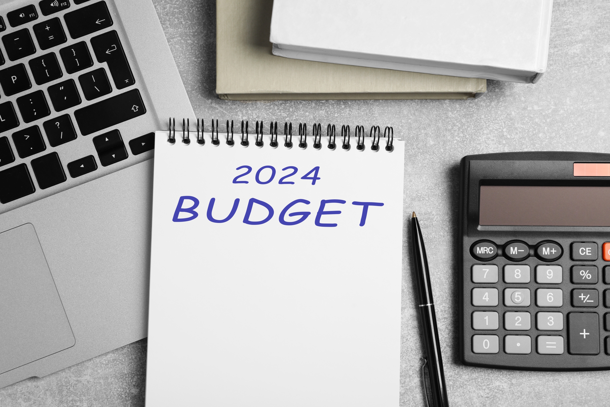 Notebook with word 2024 Budget, calculator and laptop on light table, flat lay