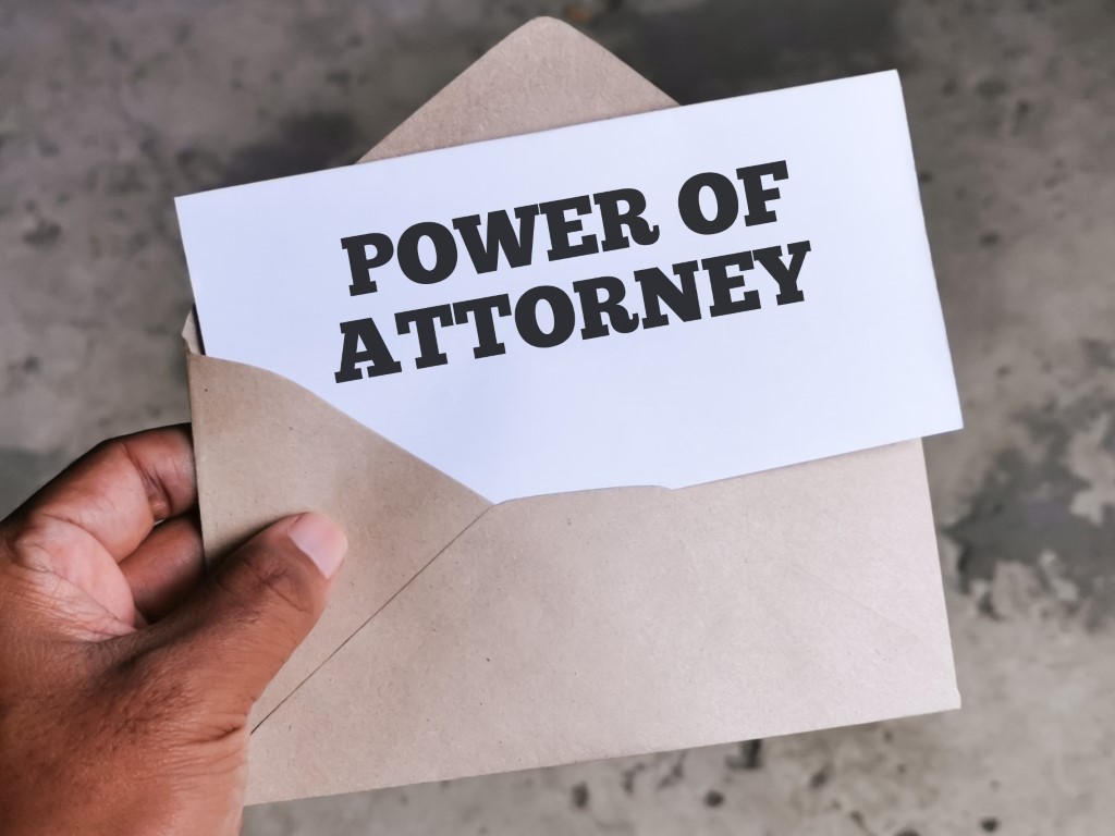 Selective focus image with noise effect hand holding envelope with white card written text POWER OF ATTORNEY. How to contest a power of attorney