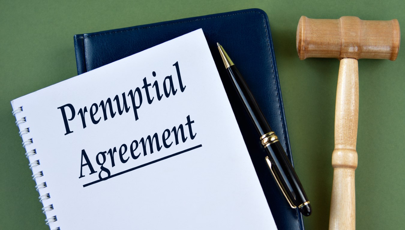 PRENUPTIAL AGREEMENT- words on a white sheet with a judge's gavel An image of a notebook with pre nuptial agreement written on the cover