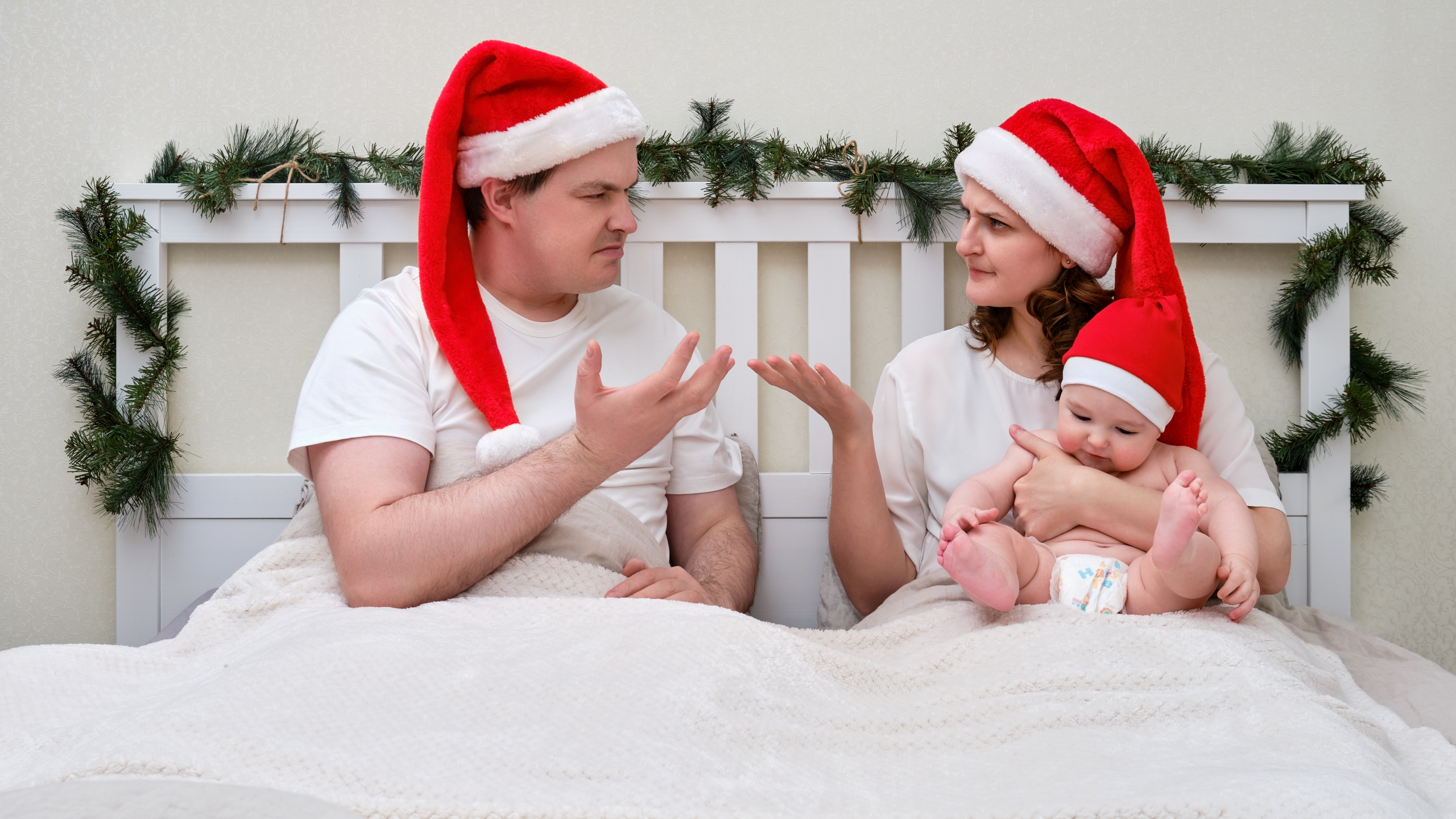 Swearing woman and man with baby on bed decorated for christmas and new year, couple in home bedroom An article debunking the myth of divorce day